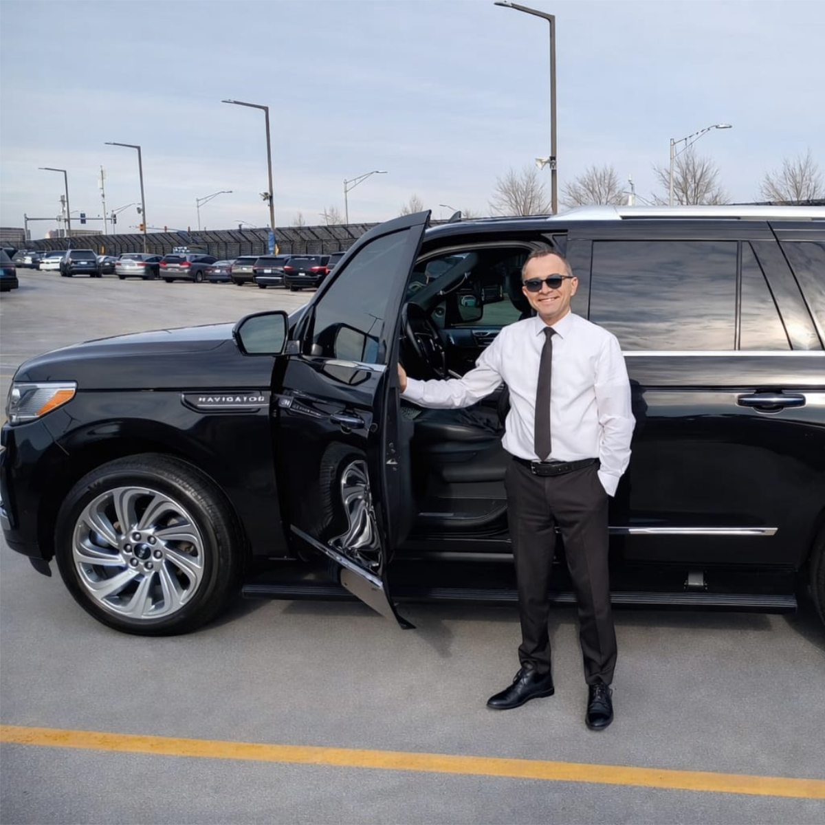 Senior executive chauffeur next to a black SUV at ORD limo lot
